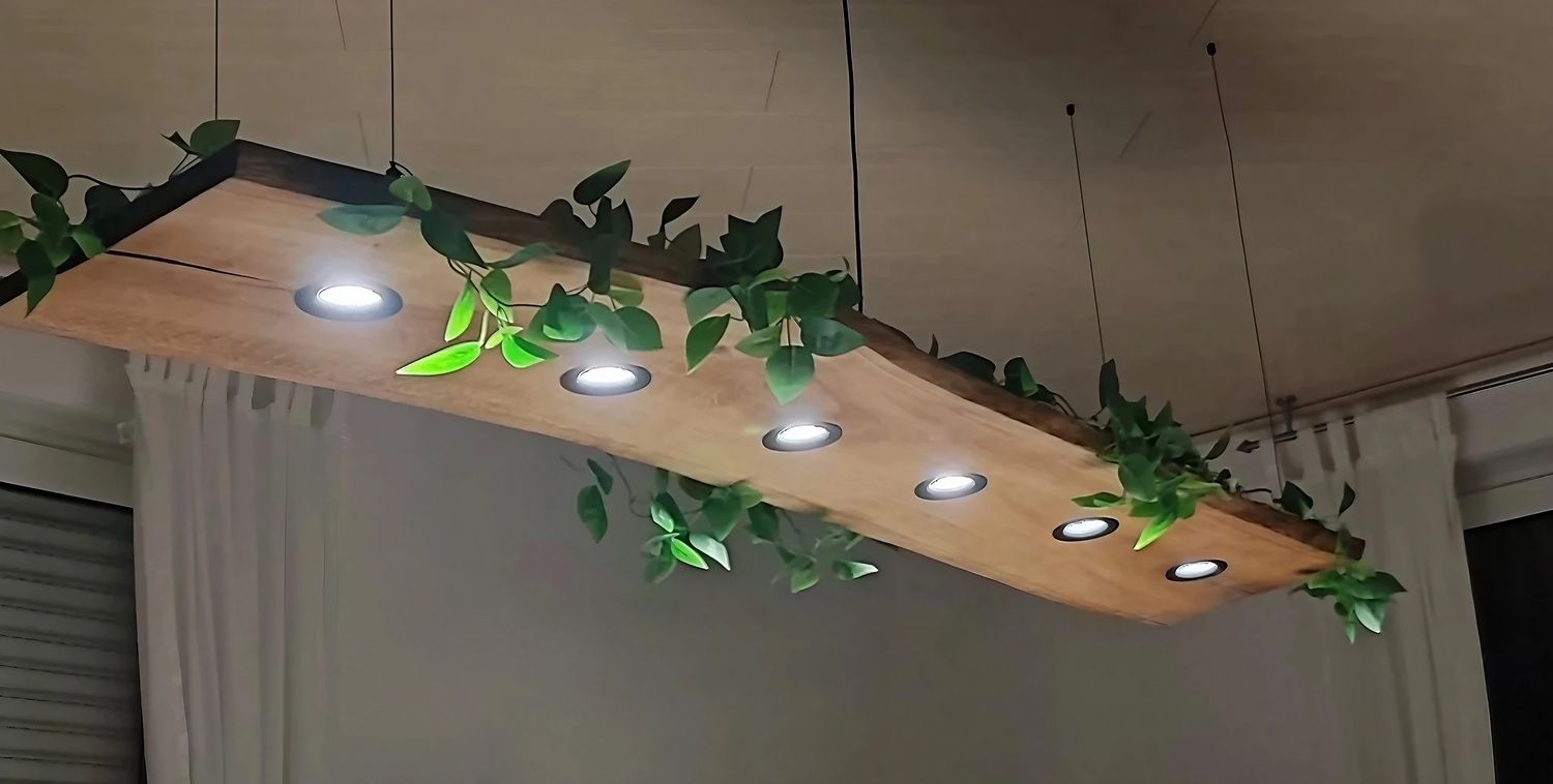 Eine moderne Holzleuchte mit sechs Einbauleuchten, umgeben von Grünpflanzen