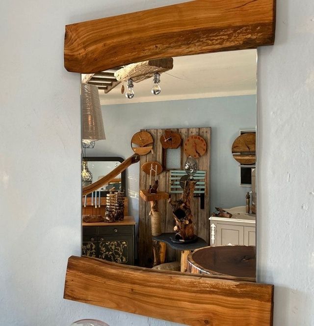 Ein holzgerahmter Spiegel spiegelt eine rustikale Einrichtung mit einzigartigem Holzdekor und Uhren an den Wänden wider